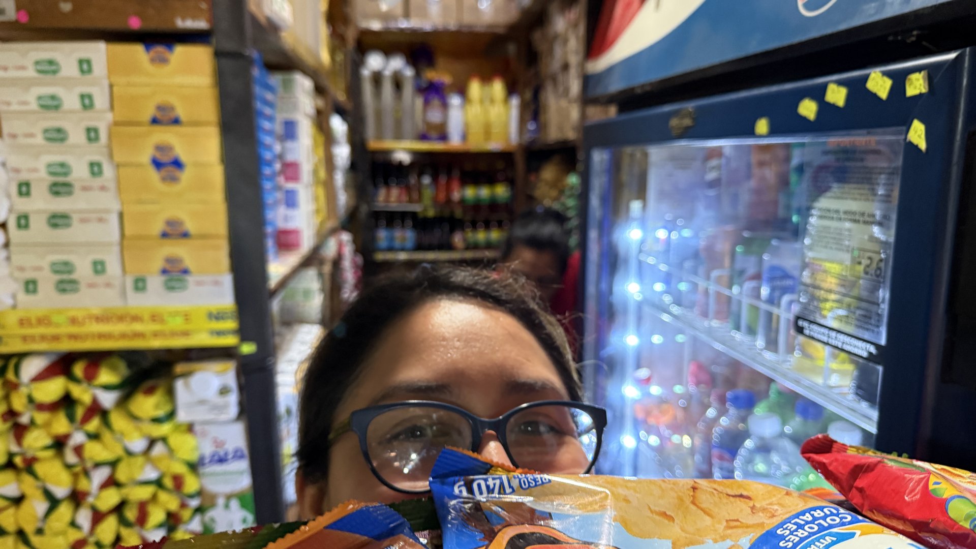 Detalle de la tienda con snacks, cooler de bebidas y abarrotes al fondo
